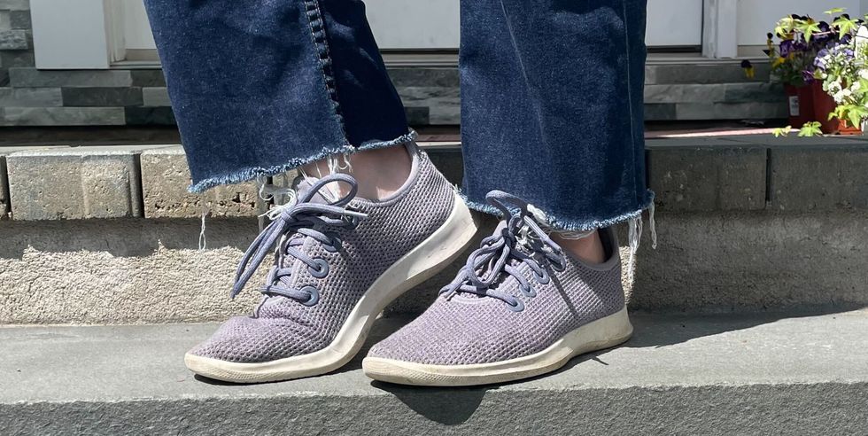 a person's feet in allbirds sneakers against concrete steps