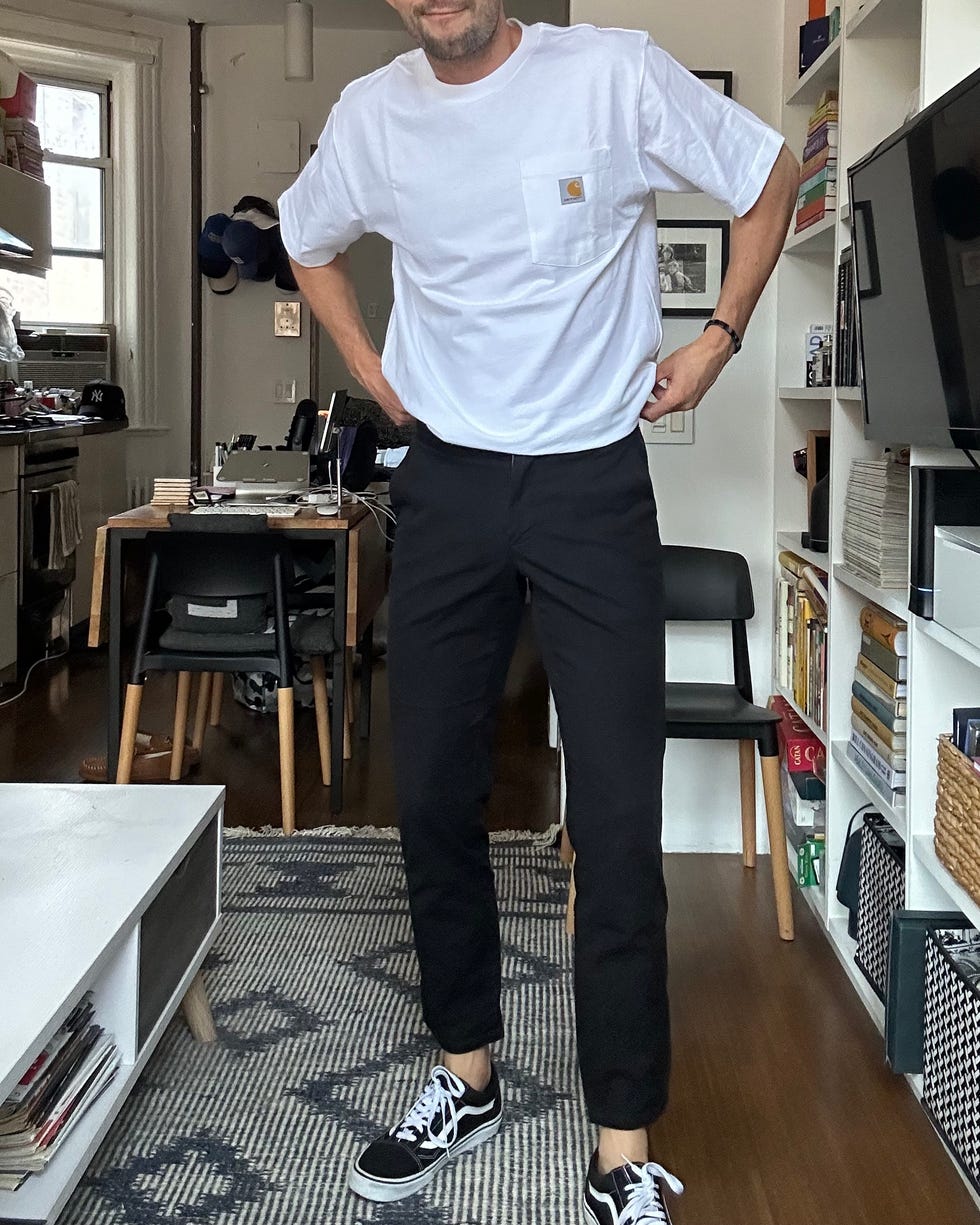 Persona de pie con ropa informal en una habitación con muebles.