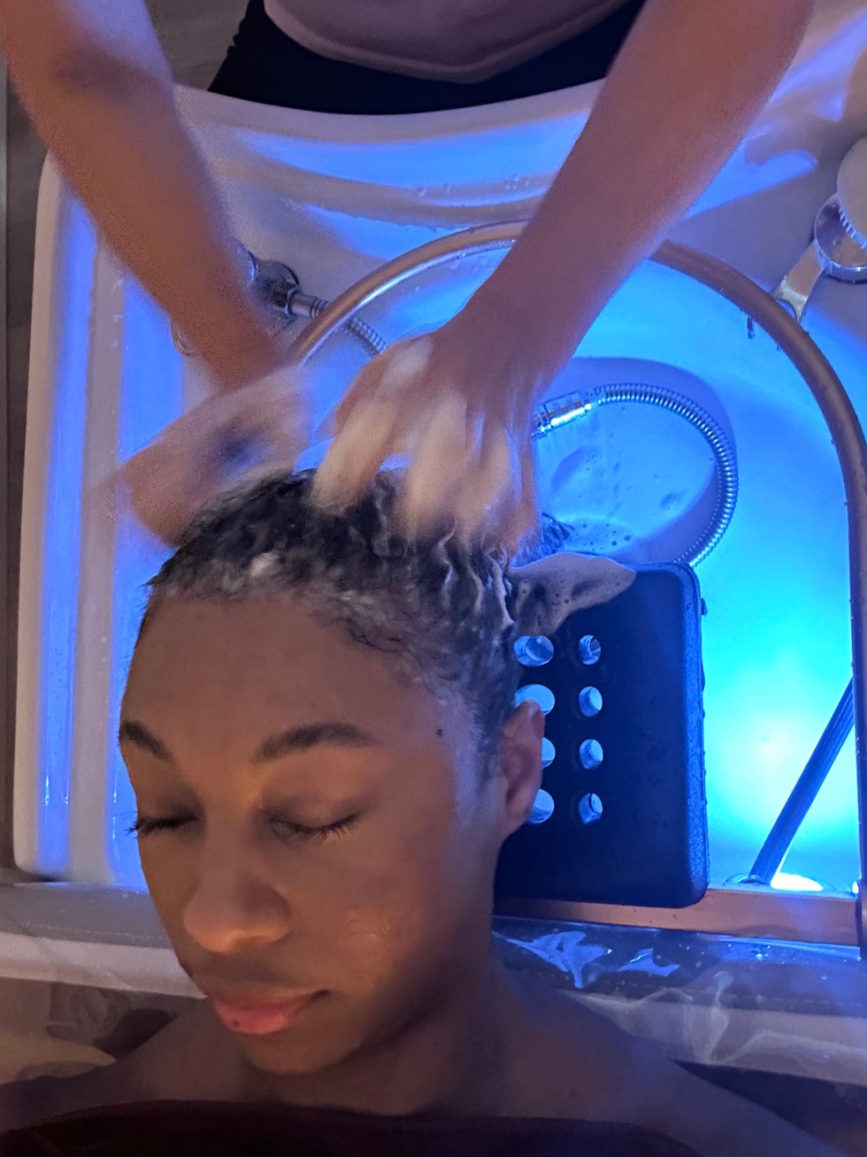 a woman getting her hair washed in a sink