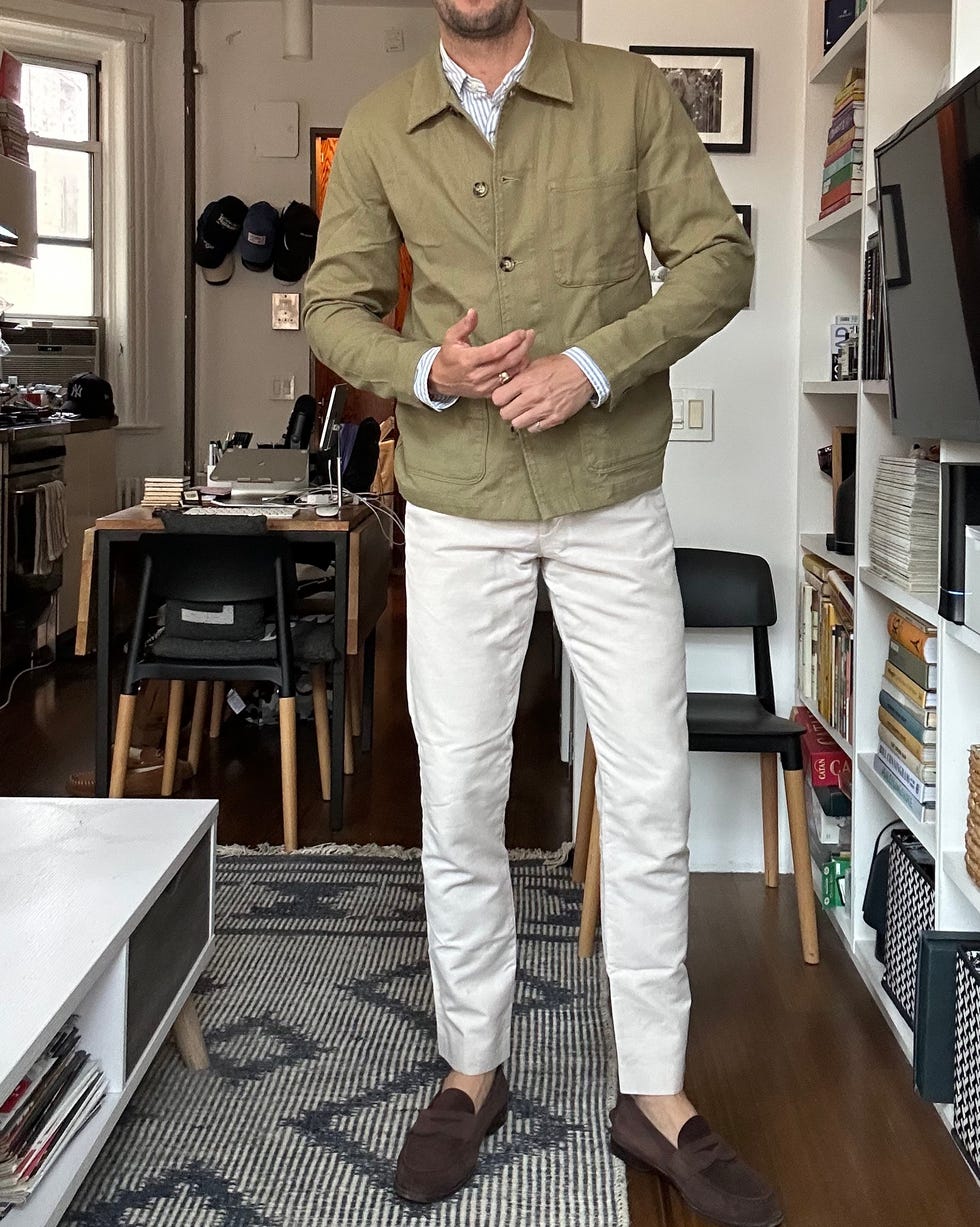 homme portant une veste olive et un pantalon blanc dans un salon