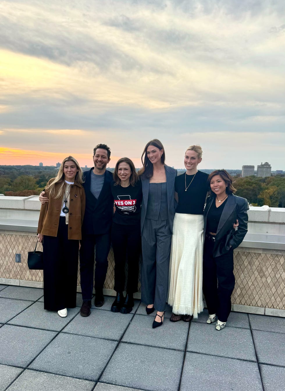 group of people posing outdoors with a sunset in the background