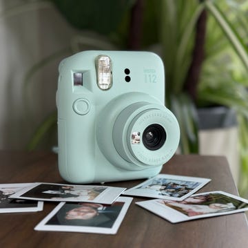 Instant camera with developed photos on a wooden surface fujifilm instax mini 12 on shelf