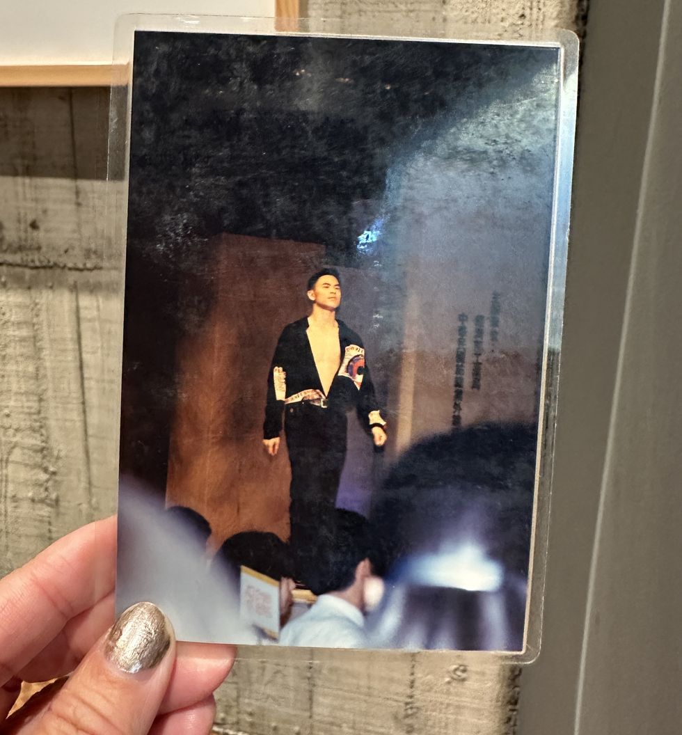 a hand holding a picture of a person in a suit