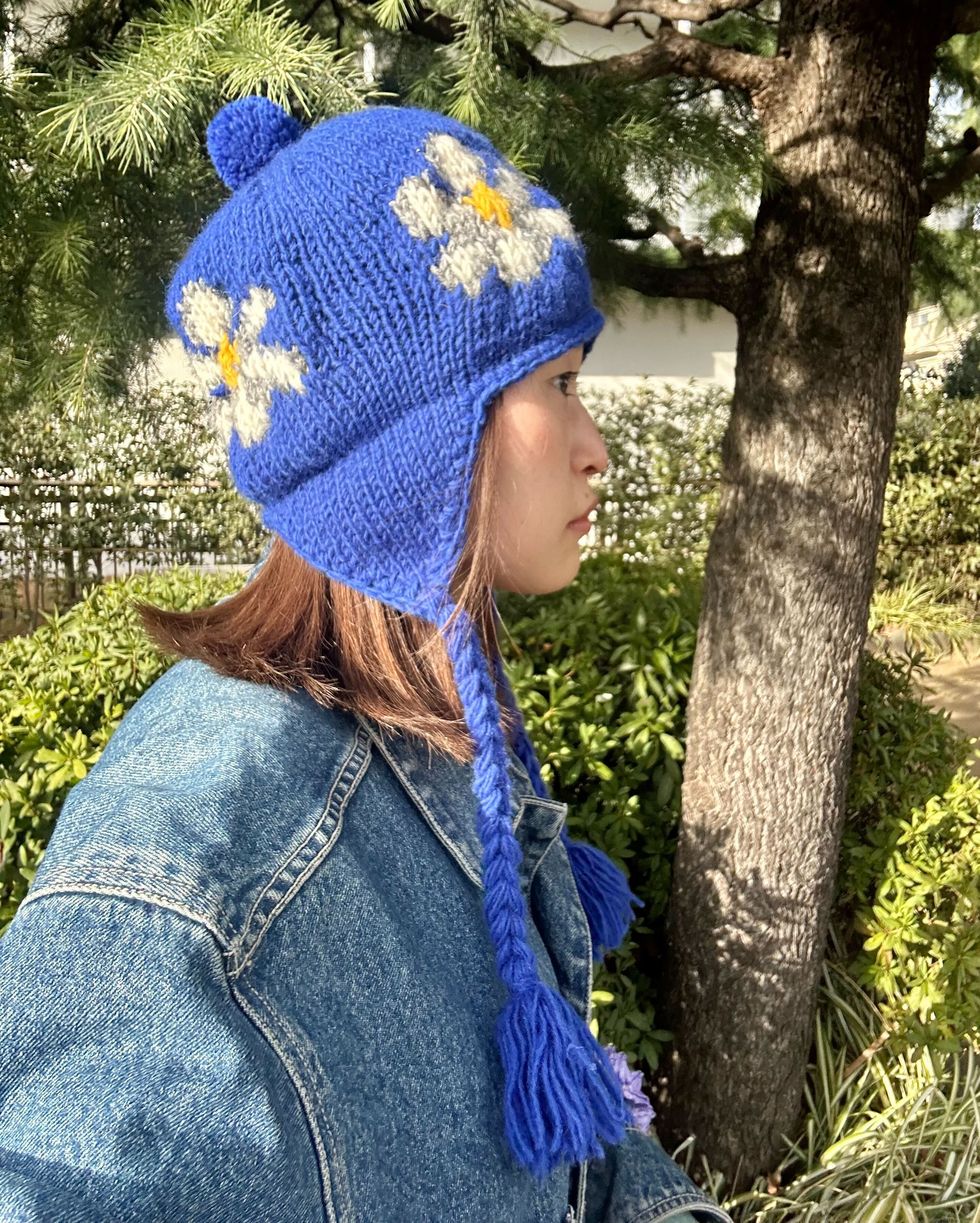 a person wearing a blue hat and scarf standing next to a tree