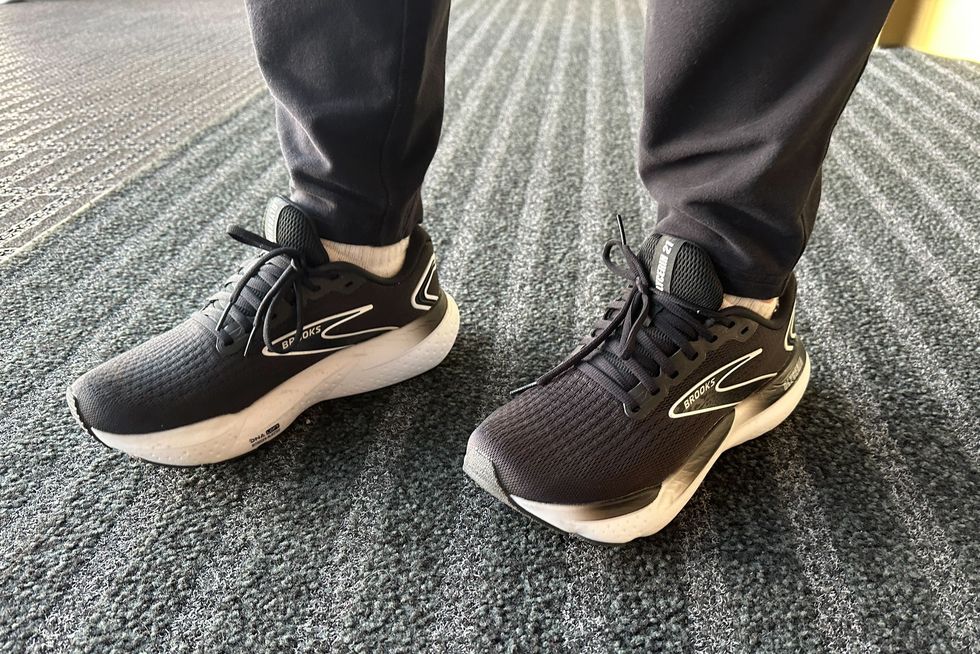 a tester wering a pair of black and white brooks glycerin 21 sneakers on a grey carpet as part of good housekeeping's testing for the best walking shoes for men