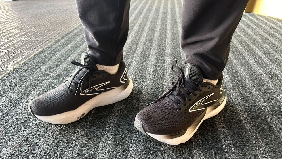 a tester wering a pair of black and white brooks glycerin 21 sneakers on a grey carpet as part of good housekeeping's testing for the best walking shoes for men