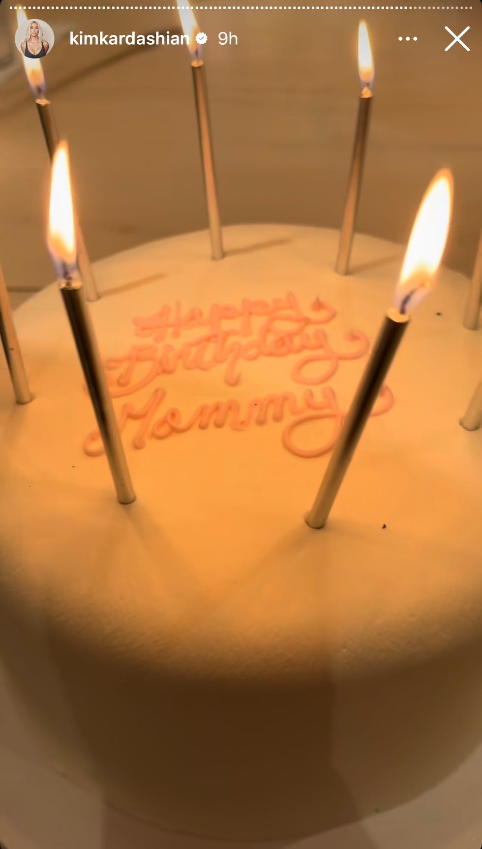 A round birthday cake is covered in pink icing with the words 