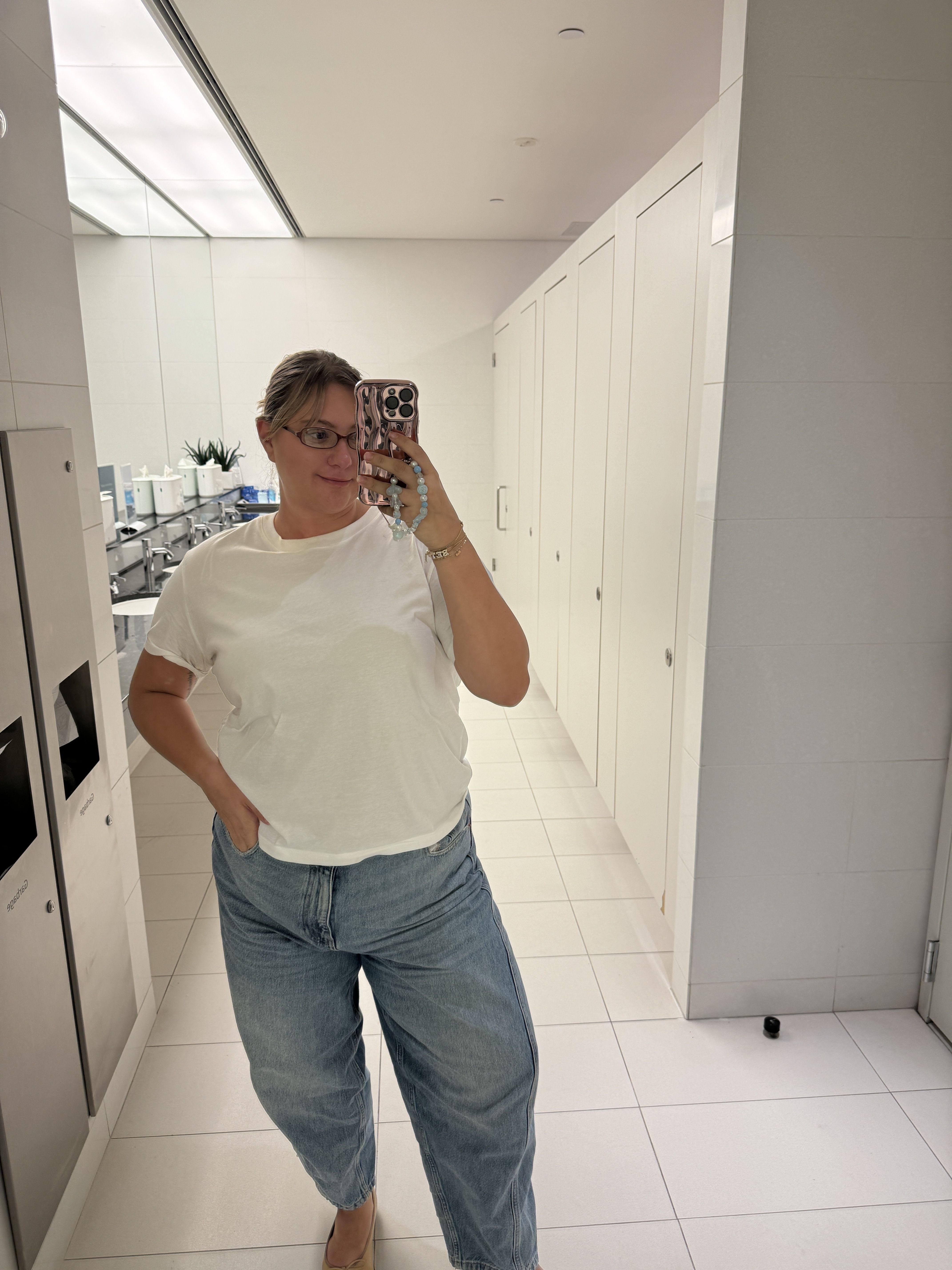selfie in a bathroom mirror showing casual attire and bathroom fixtures