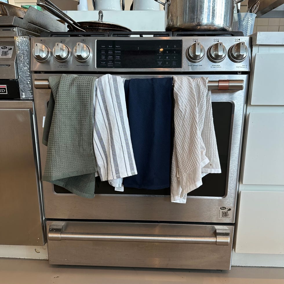four kitchen towels hanging on an oven's handle bar