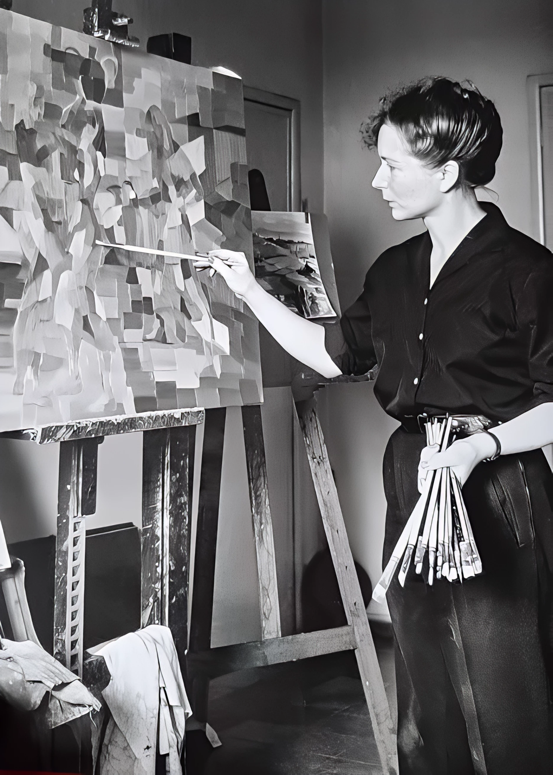 artist painting on an easel with brushes in hand
