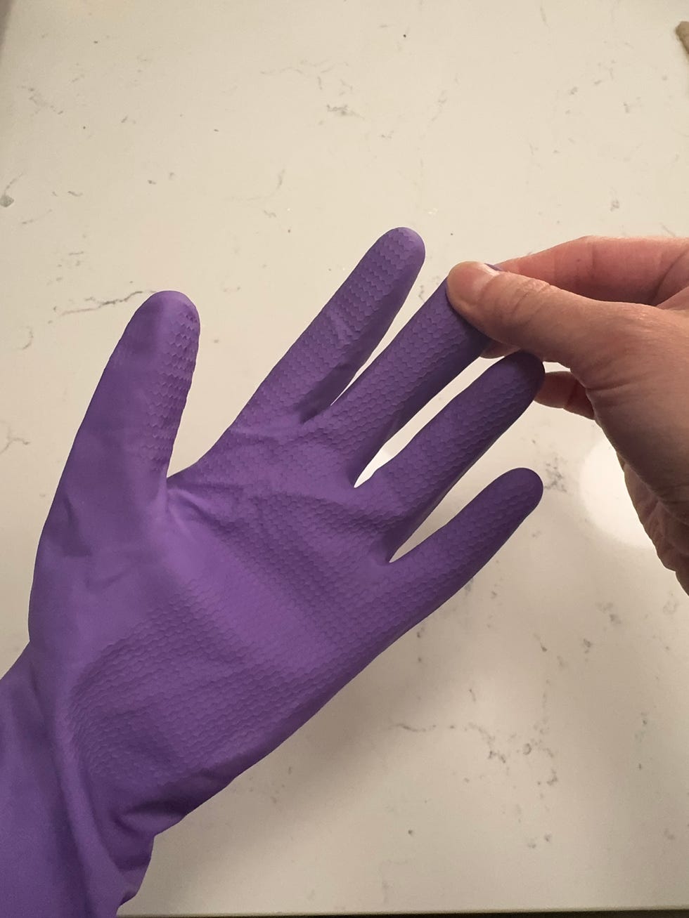 a hand wearing a purple rubber glove with fingers slightly spread