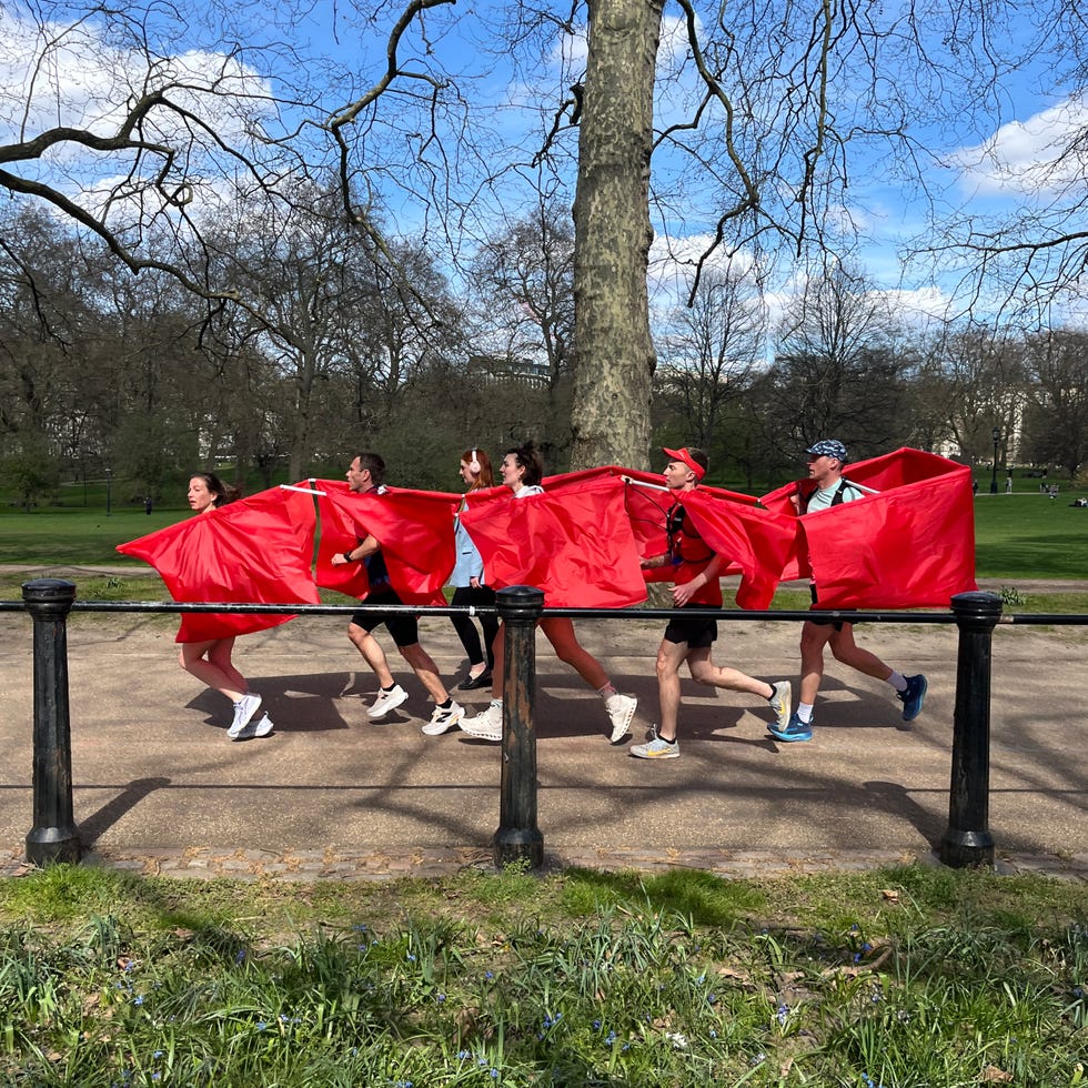 group of runners wearing a red bus costume in a park