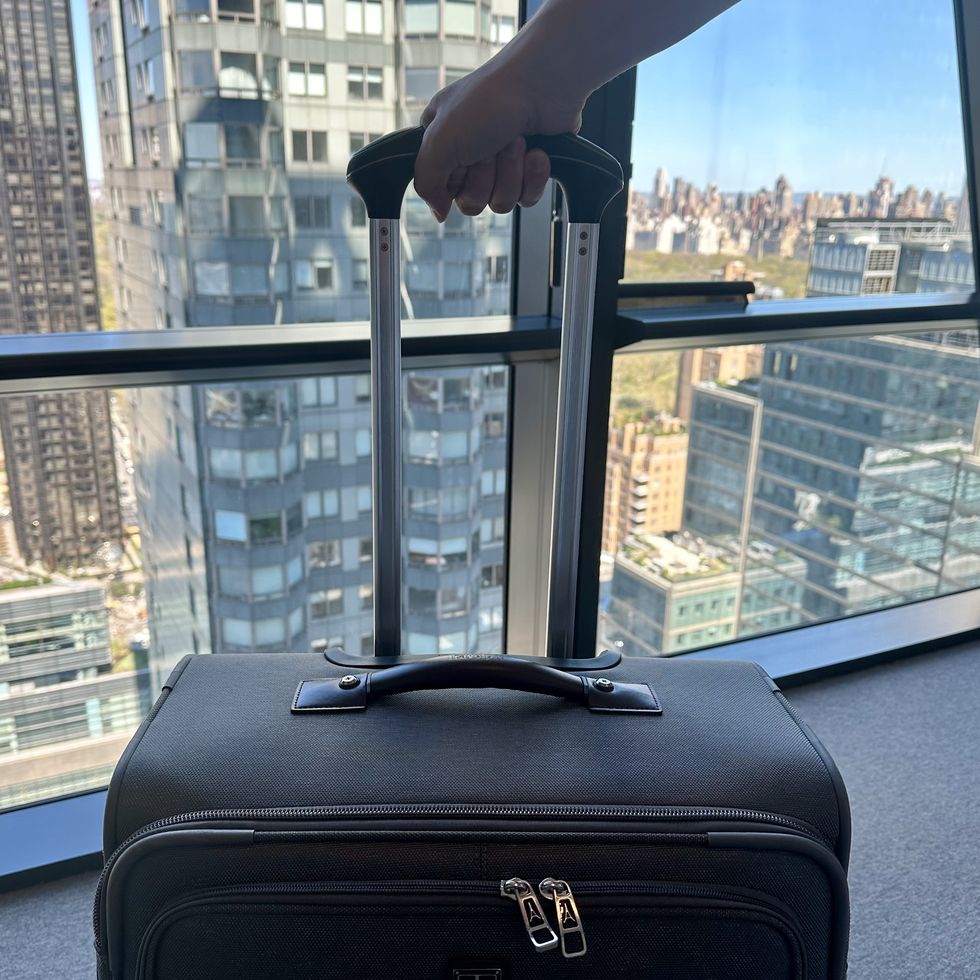 a person holding the handle of a travelpro suitcase