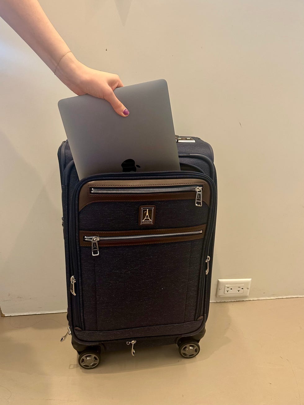 someone placing a laptop inside the travelpro carry on suitcase