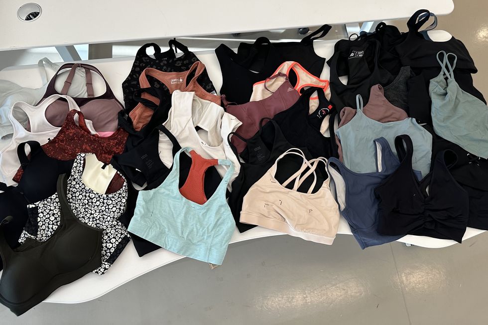 a variety of sports bras spread out on a white table, good housekeeping's testing for the best sports bras