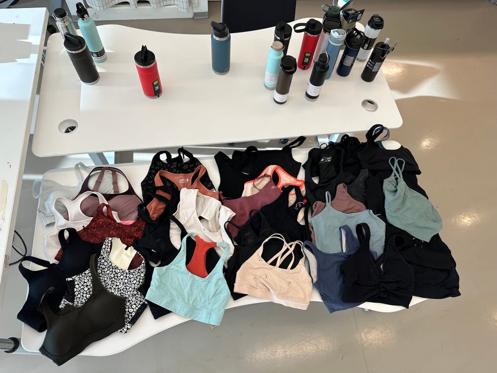 a variety of sports bras spread out on a white table, good housekeeping's testing for the best sports bras