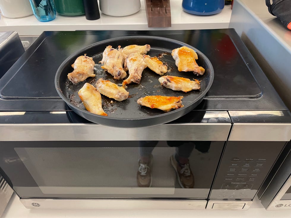 cooked chicken wings on a black pan atop a ge microwave