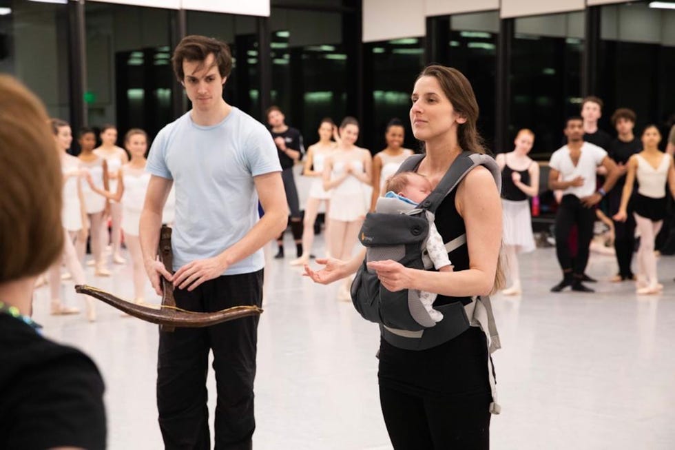 rehearsal scene with dancers and a parent holding a baby