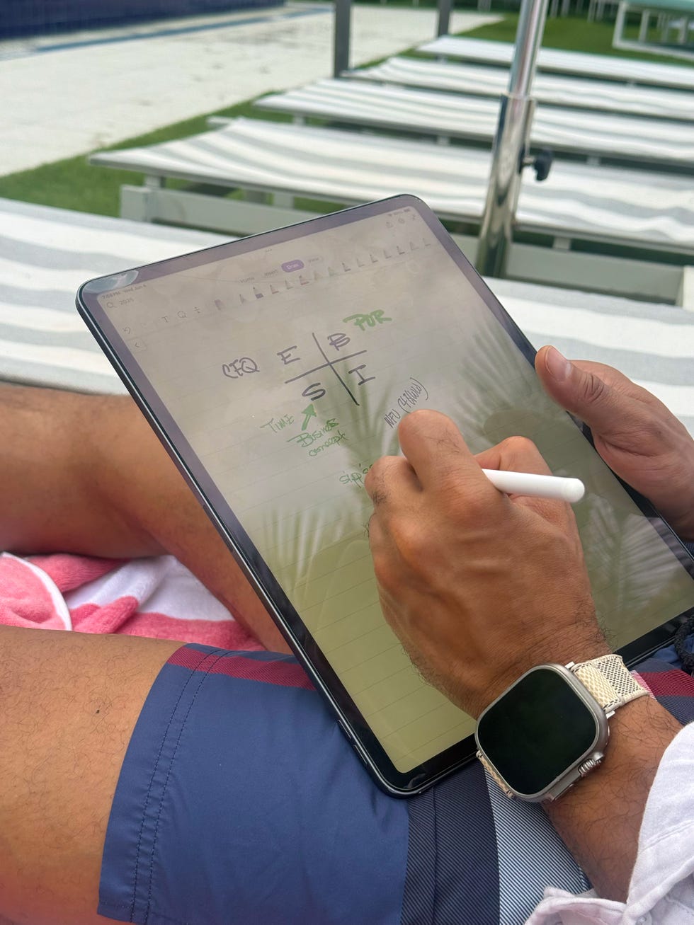 the authors husband writing on a tablet at the pool