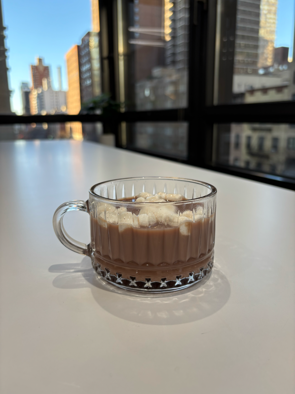 a glass of hot chocolate topped with marshmallows on a table