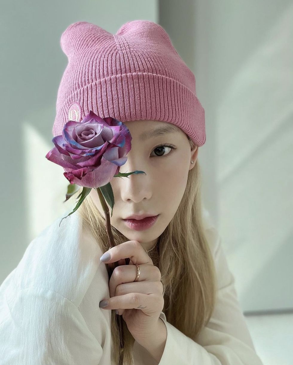 a person wearing a pink hat and holding a purple flower