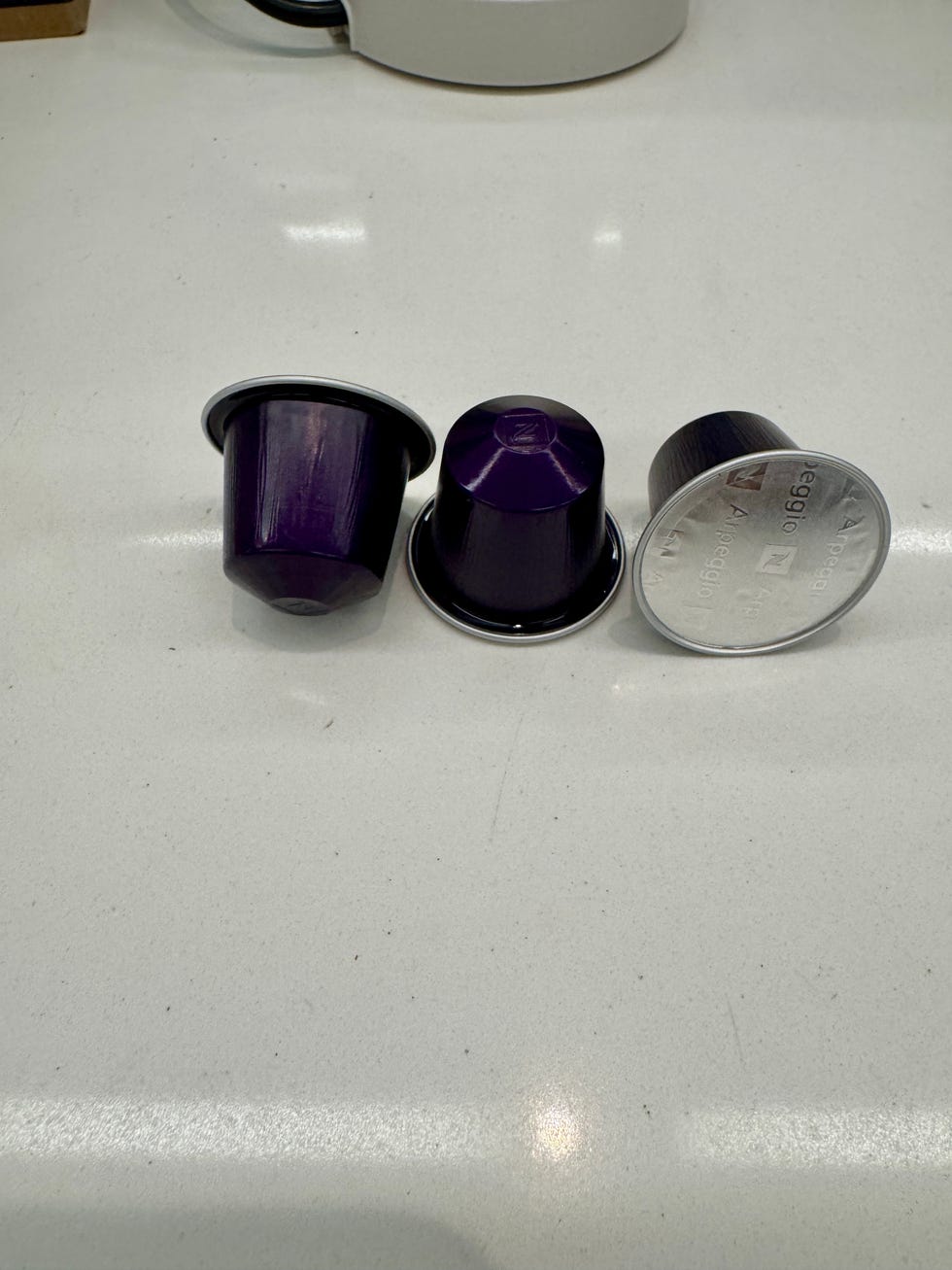 three purple nespresso coffee capsules ready for use on a counter