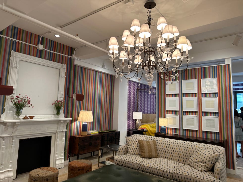 Living room model with upholstered sofas, chandelier, cream mantel and rows of prints on the walls