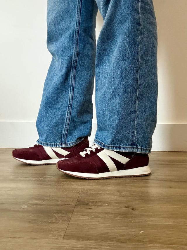 woman wearing maroon and white kizik sneakers with jeans