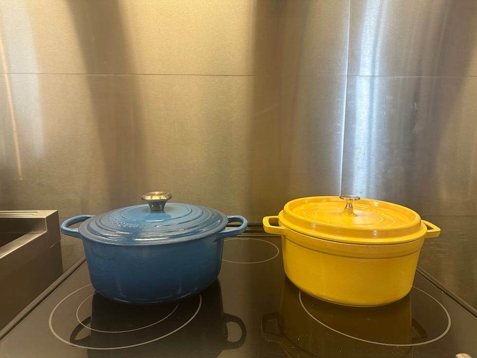 blue le crueset and yellow staub dutch ovens side by side on a cooktop