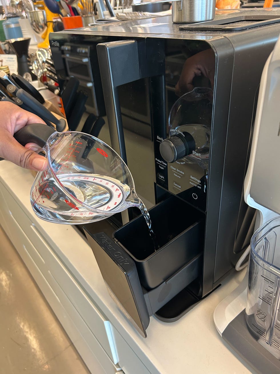 pouring water into an indoor smoker water tank