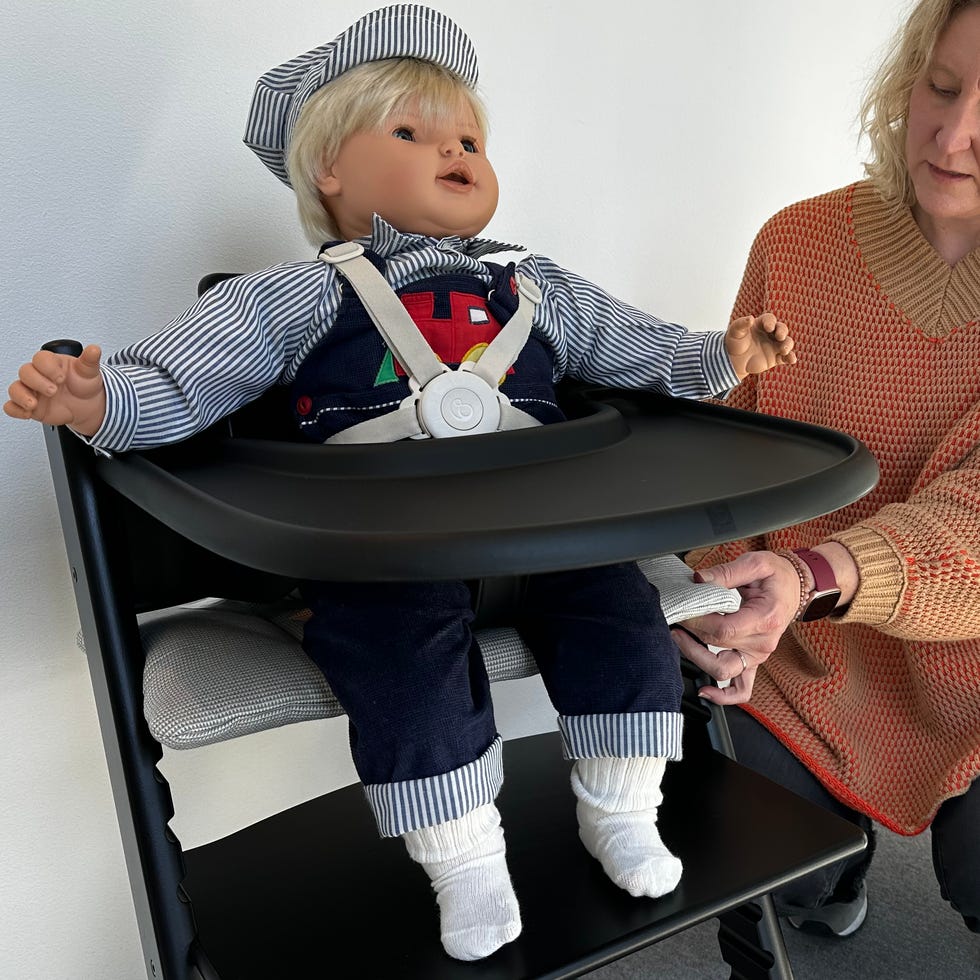 securing a doll in a Tripp Trapp high chair during testing a member of the good housekeeping institute tests a tripp trapp high chair with a doll