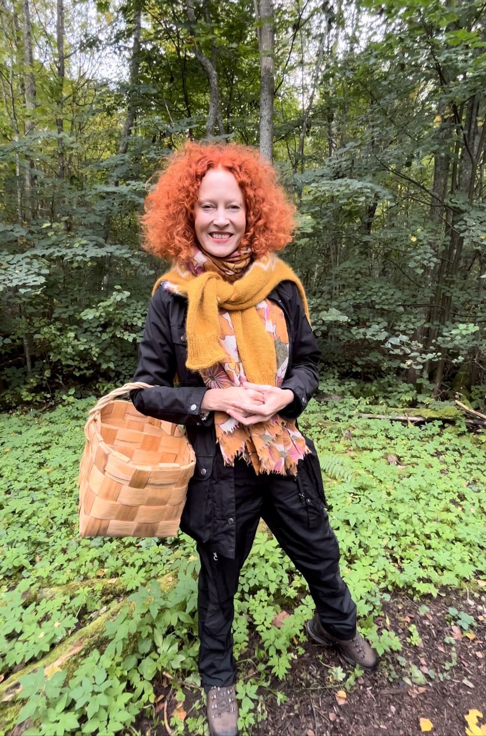 a person with red hair and a scarf standing in the woods
