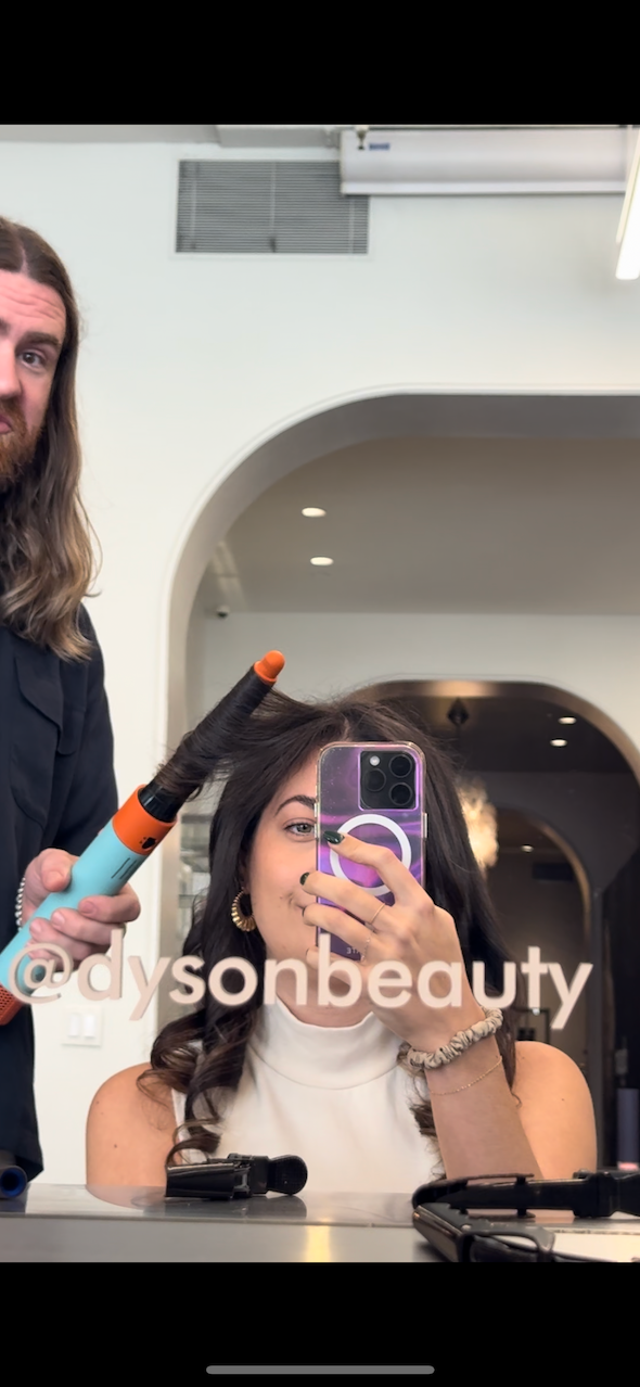 stylist using a hair curling tool on a client