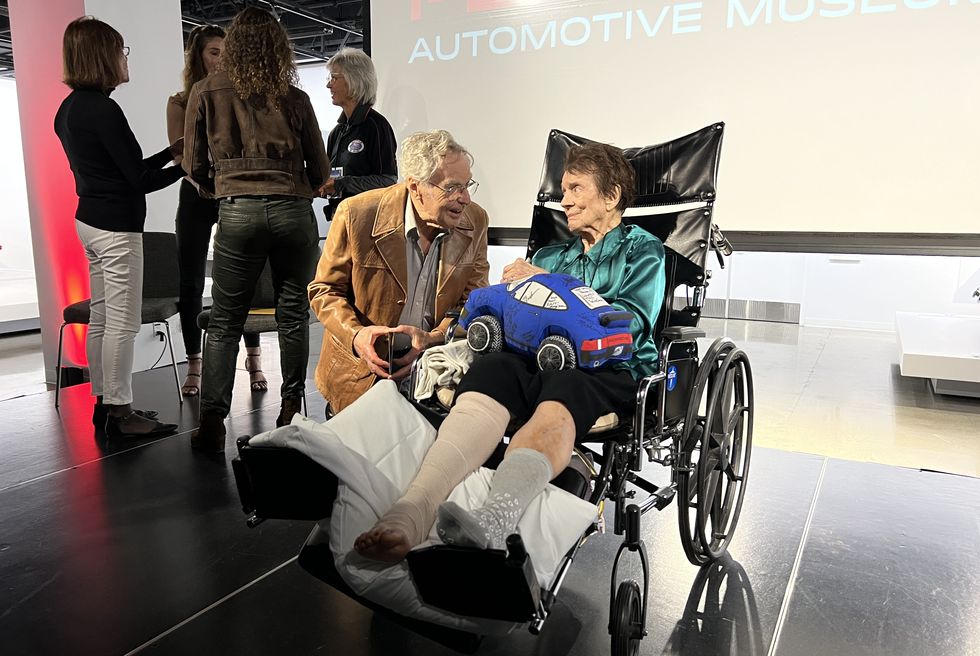 paula murphy seated in a wheelchair speaks with a friend at the petersen automotive museum
