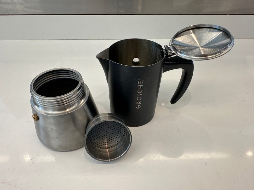 a metal brewing pot with a round base and threaded opening is positioned next to a black french press with a sturdy handle the french press has a metallic lid that is open, revealing a mesh filter inside the brewing pot features a small valve, indicating it is designed for use on a stove or heat source