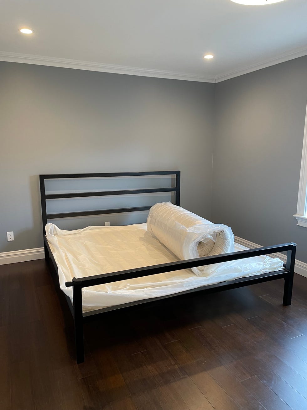 a compressed mattress rolled up on a bed frame as part of good housekeeping testing organic mattresses