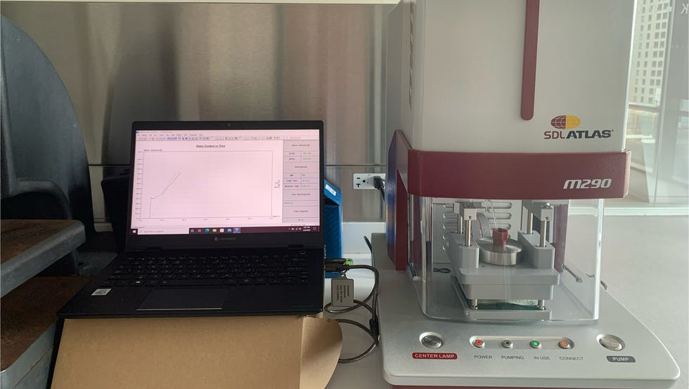 best cooling comforters - how we test 2 a moisture management tester in red and gray next to a black laptop recording fabric response and wicking speed to a sweat solution
