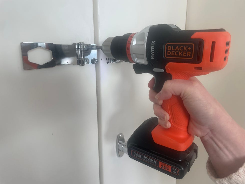 a cordless drill from black and decker is used to install a cabinet door hardware