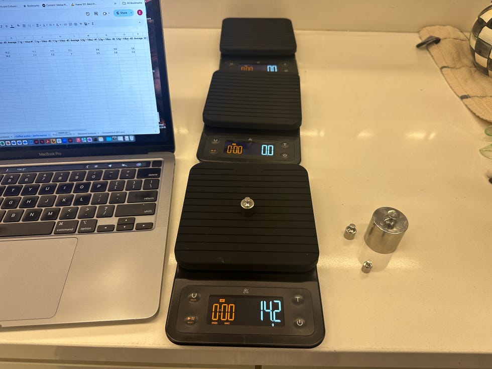 three coffee scales, one with a weight on it, next to a labtop