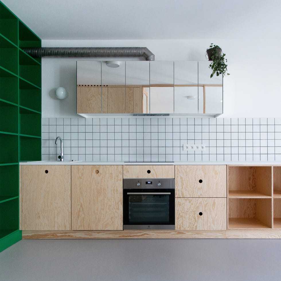 en la cocina del apartamento pequeño se combinan los frentes de madera con estanterías verdes