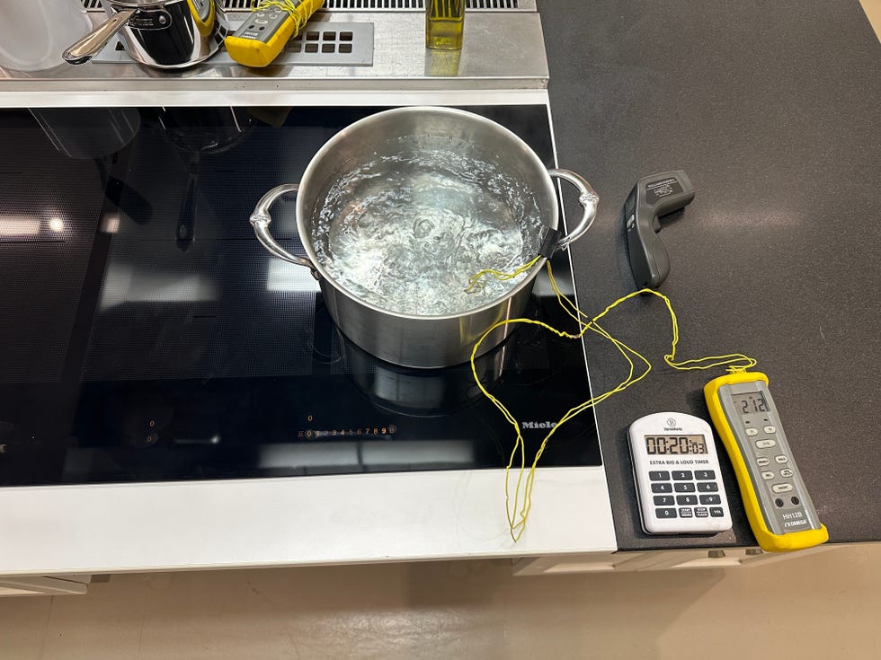 a pot of boiling water on a stovetop with thermometers and timers