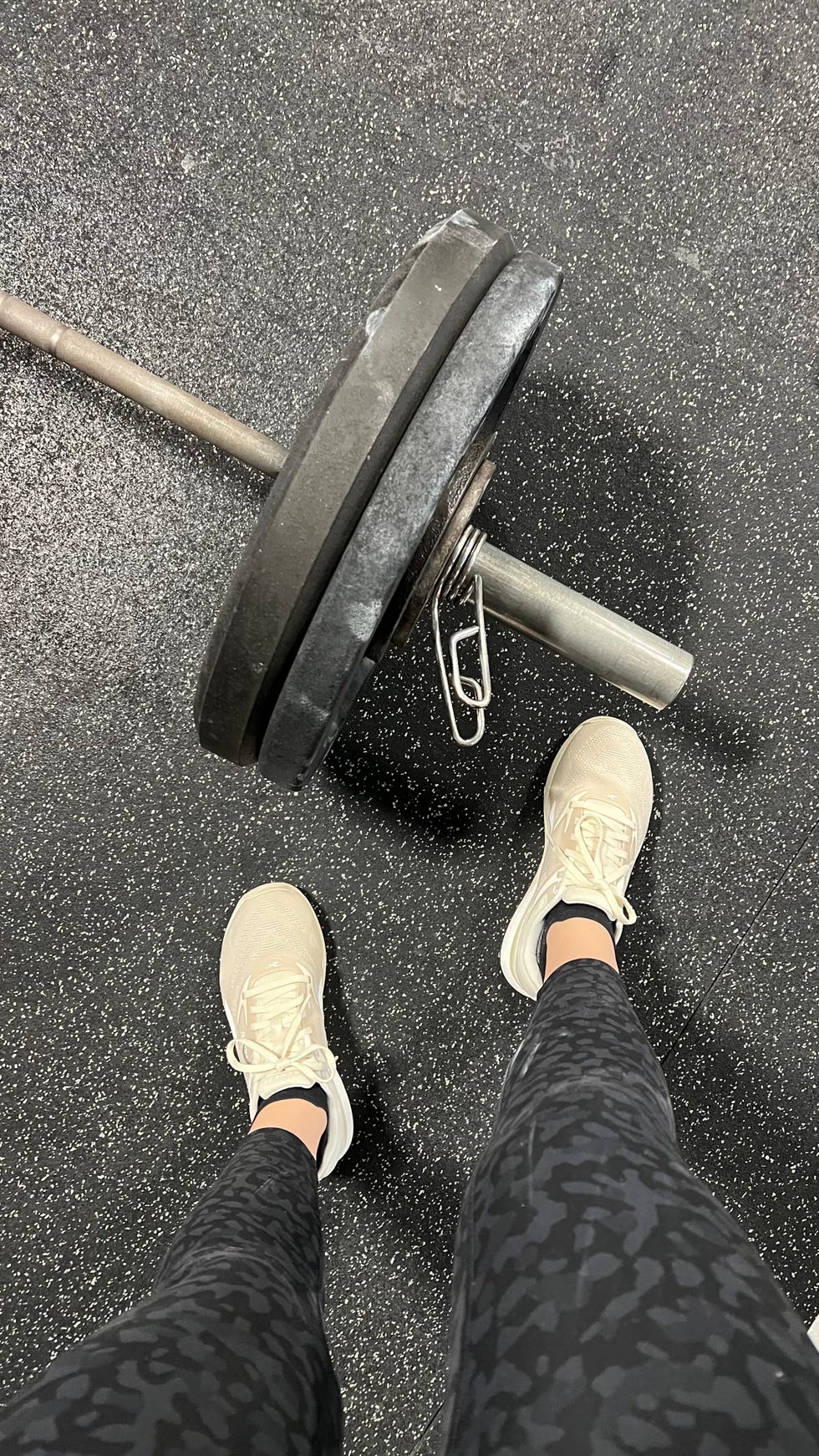 overhead shot of someone wearing the reebok nano x4 sneakers next to a large weight