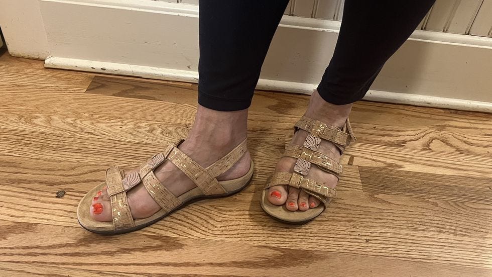 a woman modeling vionic sandals against a wooden floor