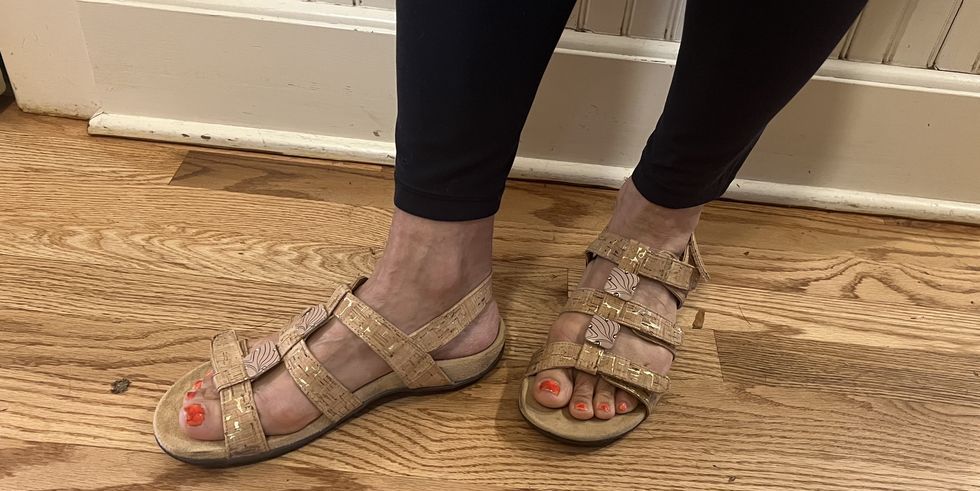 a woman modeling vionic sandals against a wooden floor