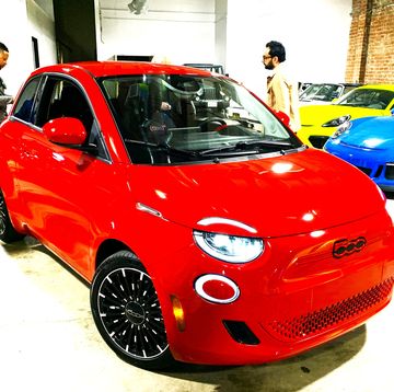a red 2024 fiat 500e parked in a showroom with other cars
