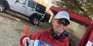 pam reed holding a cake celebrating the completion of her 100th 100mile race