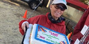 pam reed holding a cake celebrating the completion of her 100th 100mile race