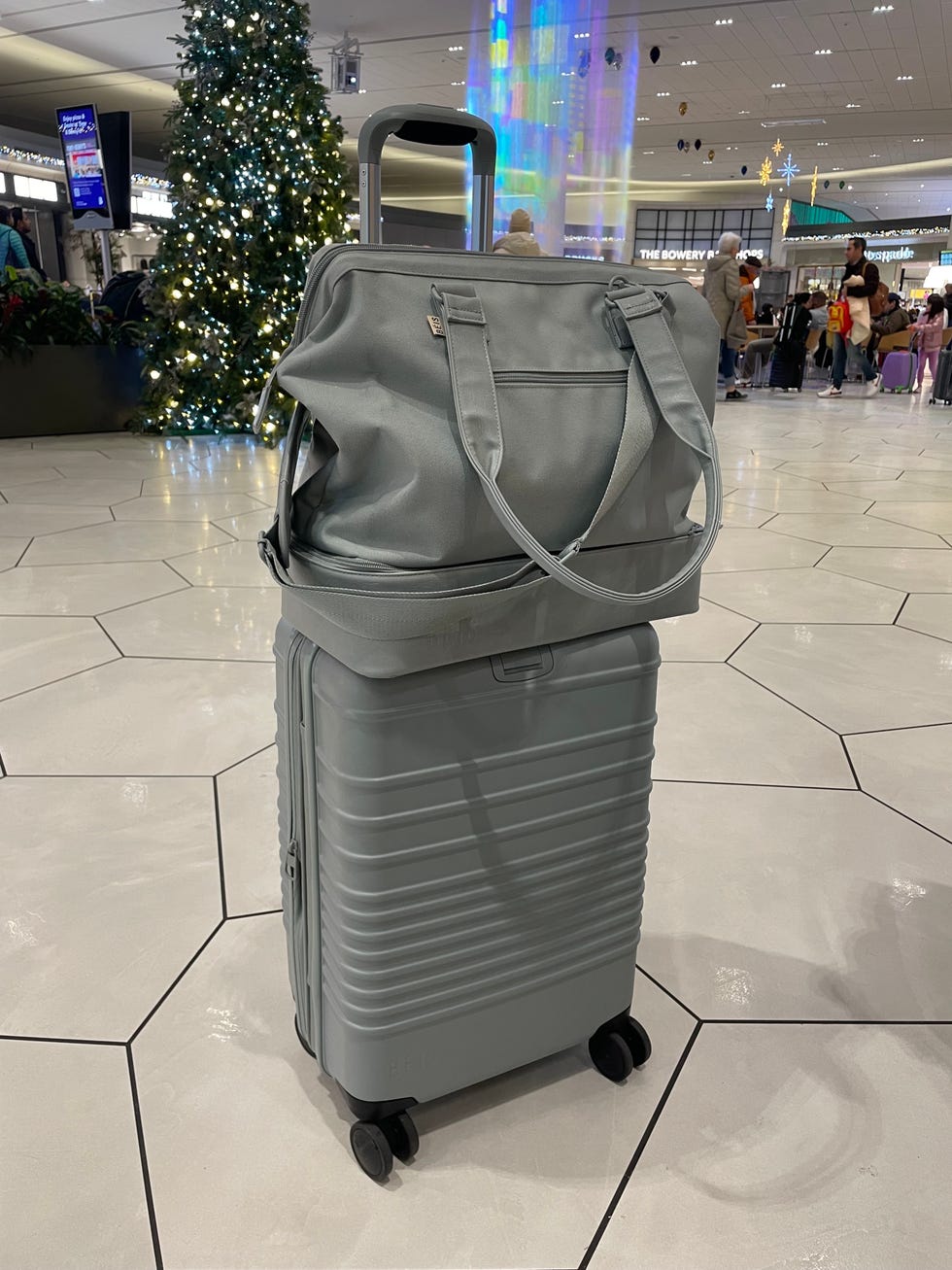 emma seymour snaps a photo of her beis weekender bag and checked bag at the airport