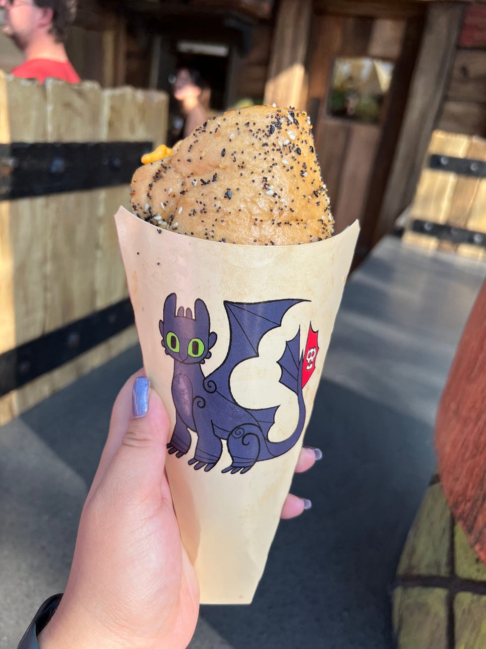 a hand holding a cone filled with a dessert featuring a cartoon dragon design