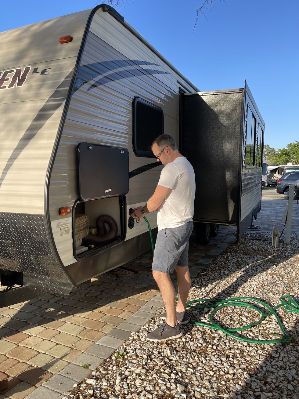extremely handsome man hooking up water hose to rv trailer